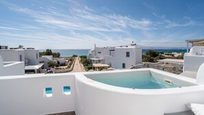 Ein Pool auf dem Dach mit Blick auf das Meer, weiße Gebäude und einen klaren Himmel.