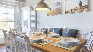 A dining area with a wooden table set for four, white chairs, and a pendant light.