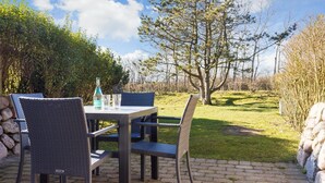 An outdoor patio with a table and chairs, a bottle of water, and a glass.