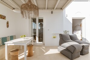 A modern living room with a white table, grey sofa, and a woven ceiling light fixture.