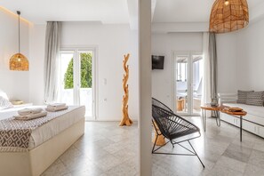 A modern hotel room with a bed, a wooden sculpture, a black chair, a small table, and a TV.