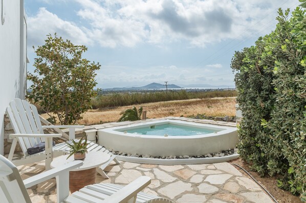 A pool area with lounge chairs, a hot tub, and a view of the landscape.