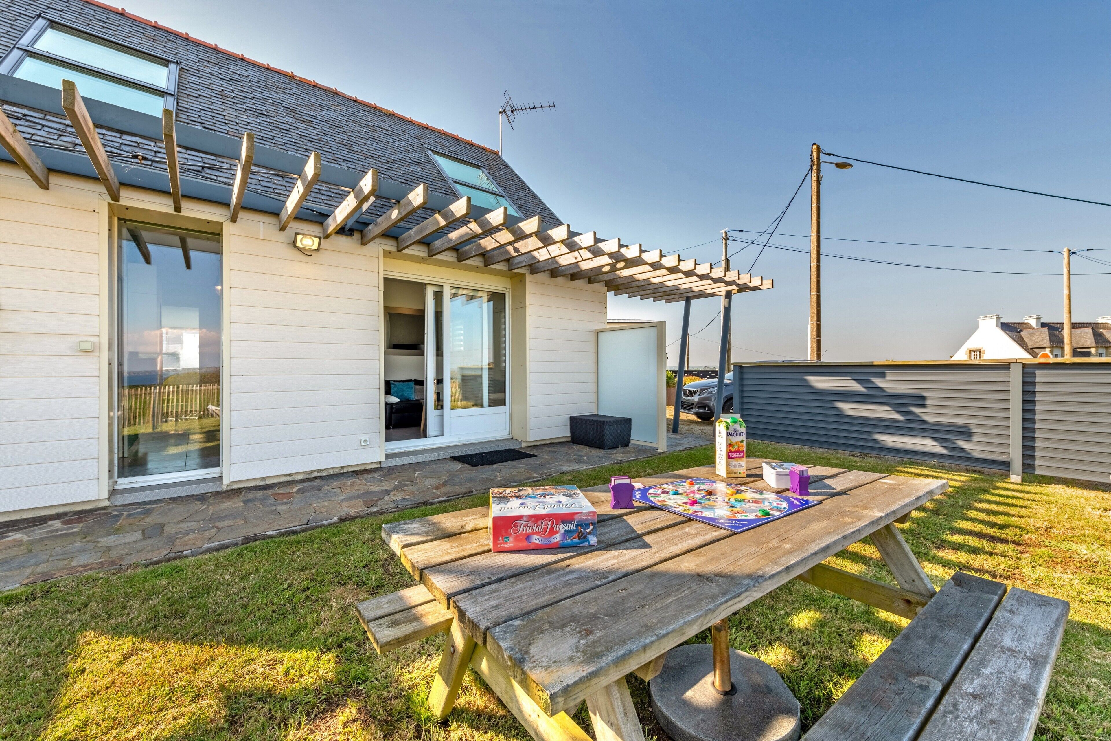 A house with a patio, a wooden table with a board game, and a sliding glass door.