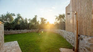 A backyard with a stone wall, a wooden deck, and a bamboo fence. - Villa Nora in Ditiki Mani (West Mani)