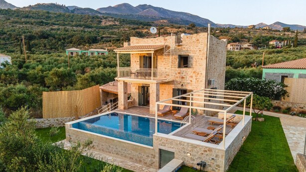 A two-story stone house with a swimming pool, a balcony, and a view of the surrounding hills. - Villa Nora in Ditiki Mani (West Mani)