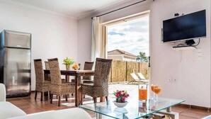 A modern kitchen with a stainless steel refrigerator, wicker chairs around a glass table, and a TV mounted on the wall. - Villa Alex in Ionian Islands (Kefalonia)