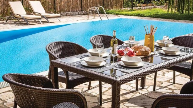 A poolside dining area with wicker chairs, a glass table, and a pool in the background. - Villa Alex in Ionian Islands (Kefalonia)