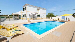 A two-story building with a swimming pool, sun loungers, and a covered patio area. - Villa Sol Nascente in Porches (Silves)