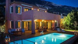 Une maison moderne à deux étages, dotée d’une piscine, de mobilier d’extérieur et offrant une vue sur les montagnes.