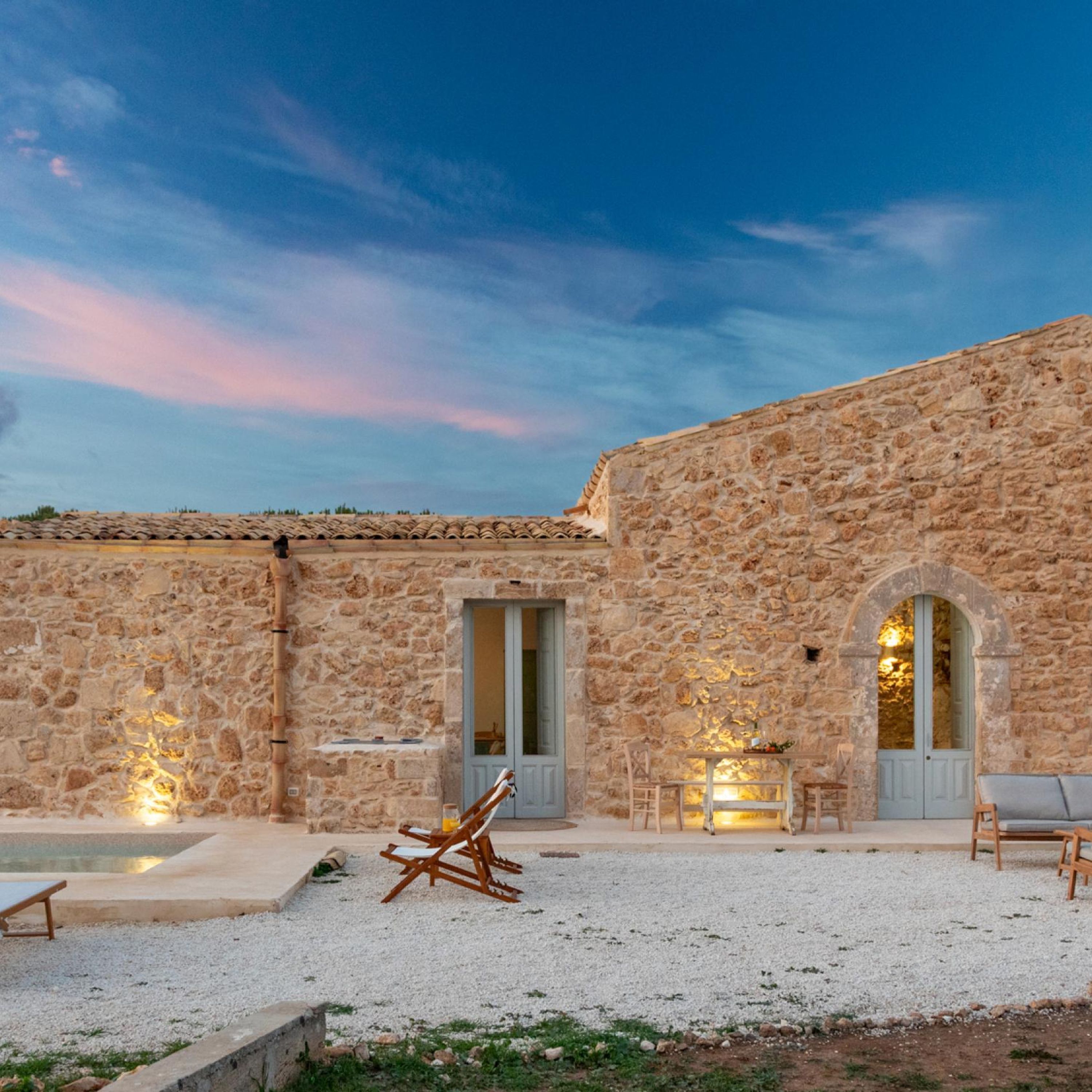 A stone building with a courtyard, outdoor seating, and a pool.