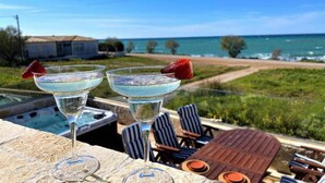 Two cocktails with strawberries on a balcony overlooking a beach and ocean.