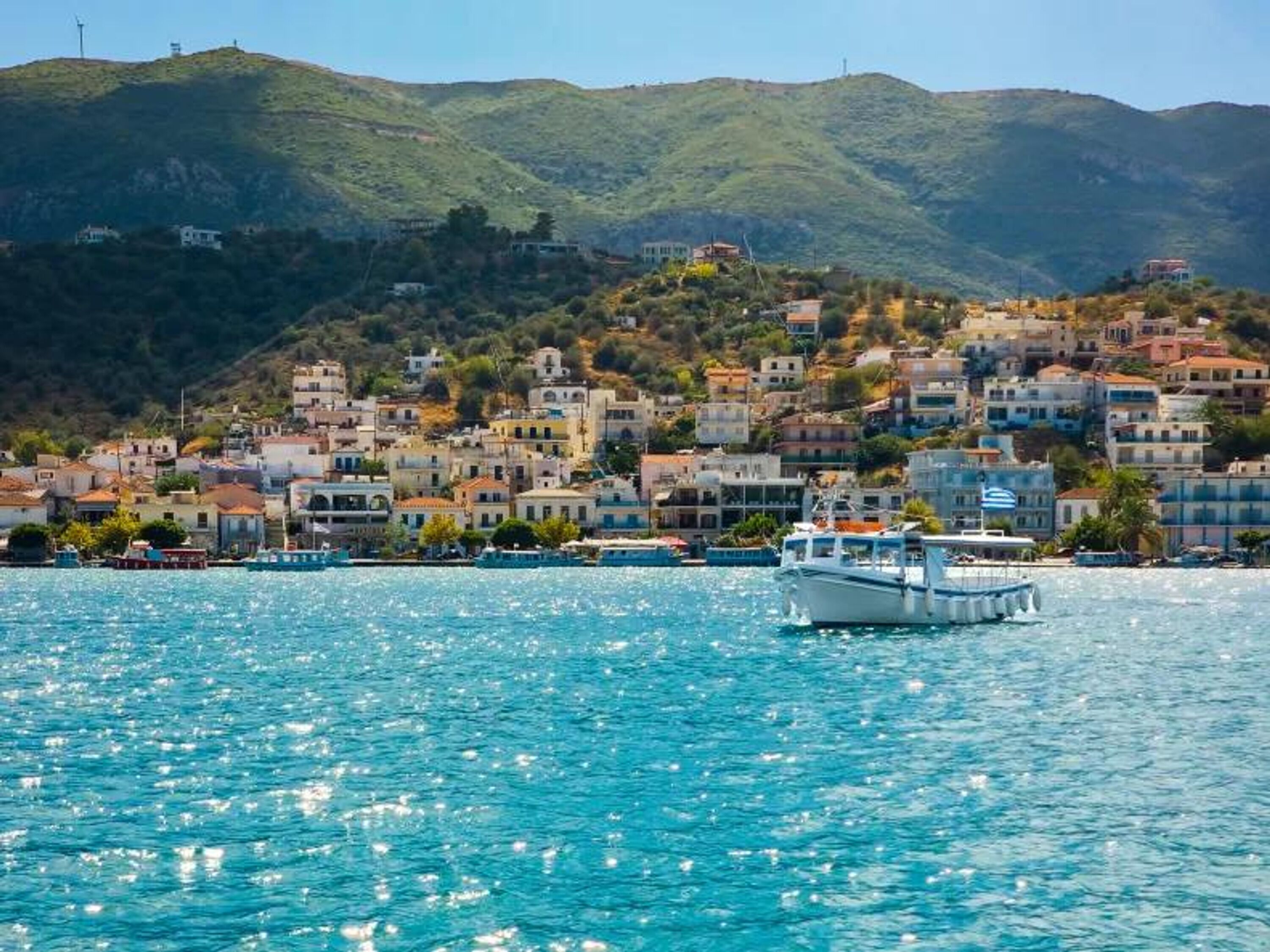 A coastal town with buildings on a hillside and a boat in the water.