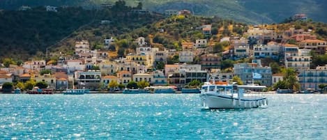A coastal town with buildings on a hillside and a boat in the water.