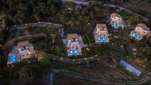 Une vue aérienne d’un quartier résidentiel composé de plusieurs maisons, chacune dotée d’une piscine et d’un éclairage extérieur.