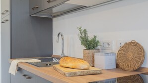 Una cocina moderna con encimera de madera, pileta de acero inoxidable, hogaza de pan, planta en maceta y cestas tejidas.