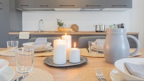 Una cocina moderna con armarios grises, una jarra grande color gris y tres velas encendidas sobre la mesa.