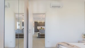 Una habitación de hotel moderna con una cama, una mesita de noche y vistas al área de estar contigua.