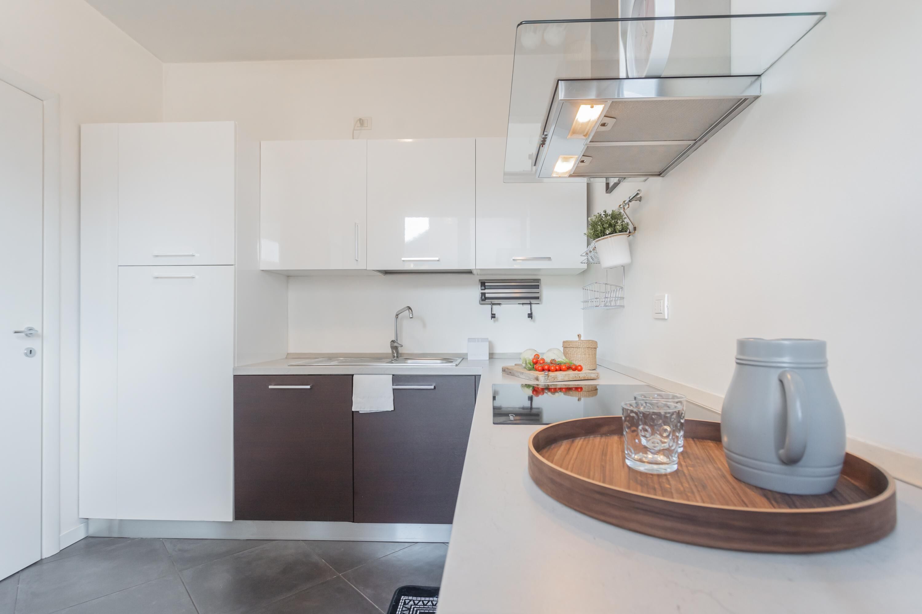 A modern kitchen with white cabinets, a stainless steel sink, and a wooden countertop.