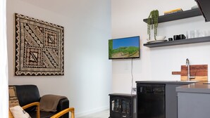 A modern kitchen with a built-in dishwasher, a flat-screen TV, and a hanging plant. - Stunning Matakana Retreat! (Matakana)