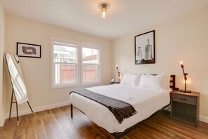Relax in a serene bedroom with a large bed, full-length mirror, and artwork.