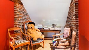 A cozy room with a brick wall, a wooden desk with books, and two wooden chairs. - Beautiful Mansion With Swimmingpool Close to Maastricht (Bilzen)