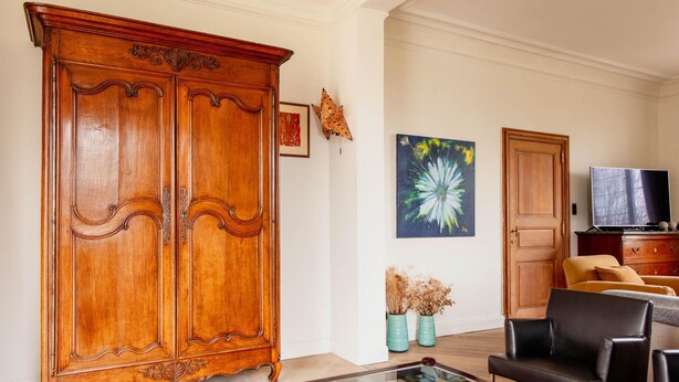 A living room with a large wooden cabinet, a glass coffee table, a sofa, and a television. - Beautiful Mansion With Swimmingpool Close to Maastricht (Bilzen)
