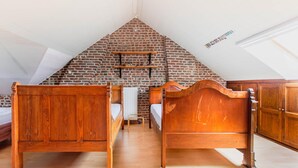 A bedroom with two wooden beds, a brick wall, and a sloped ceiling. - Beautiful Mansion With Swimmingpool Close to Maastricht (Bilzen)