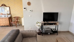 A living room with a sofa, a TV on a wooden stand, a wooden dresser, and a chair. - Lovely House in Heers With 2 Bedrooms (Heers)