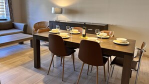 A dining area with a wooden table, four chairs, and a wine bottle. - Beautiful House With 4 Bedrooms in Hees (Bilzen)