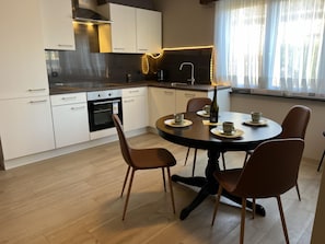 Una cucina moderna con mobili bianchi, un tavolo rotondo e quattro sedie.
