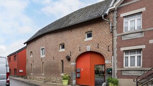 A brick building with a red door, a small window, and a staircase on the right.