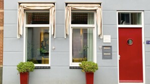A two-story building with three windows on the ground floor and a red door. - Charming Retreat in the Heart of Oud-beijerland (Oud-Beijerland)
