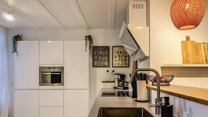 A modern kitchen with white cabinetry, a built-in oven, a stainless steel sink, and a wooden countertop. - Charming Retreat in the Heart of Oud-beijerland (Oud-Beijerland)