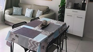 A modern living room with a sofa, dining table, and kitchen area.