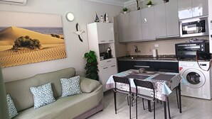 A compact living space with a sofa, dining table, and kitchenette.