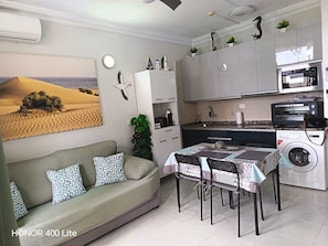A compact living space with a sofa, dining table, and kitchenette.