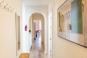 Un couloir avec un extincteur fixé au mur, un banc en bois et une porte donnant sur une autre pièce.