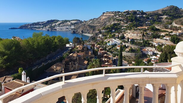 Une ville côtière avec des maisons à étages, un ciel bleu azur et une vue sur la mer.