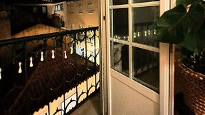 A nighttime view from a balcony with a metal railing, a window, and a potted plant. - Holiday Apartment "Atalaia Duplex" with Balcony & Wi-Fi (Lisboa)