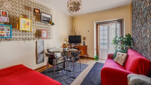 A living room with a dining table, red sofa, and a TV. - Holiday Apartment "Atalaia Duplex" with Balcony & Wi-Fi (Lisboa)