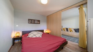 Une chambre à coucher avec un lit, des lampes de chevet, un tableau au mur et un canapé dans la pièce adjacente.