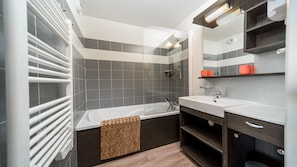 A modern bathroom with a bathtub, a sink, and a mirror. - Apartment for 6 people with mountain views, a swimming pool and parking (Allos)