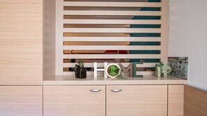 A wooden cabinet with horizontal slats, a small potted plant, and decorative items including a letter 'E' and a framed picture. - Apartment for 6 people with mountain views, a swimming pool and parking (Allos)