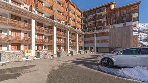 Ein mehrstöckiges Hotel mit Balkonen, einem Parkplatz und Schnee auf dem Boden.