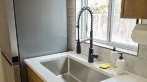 Una cocina con un lavamanos de acero inoxidable, un grifo moderno y una ventana con vistas al exterior.