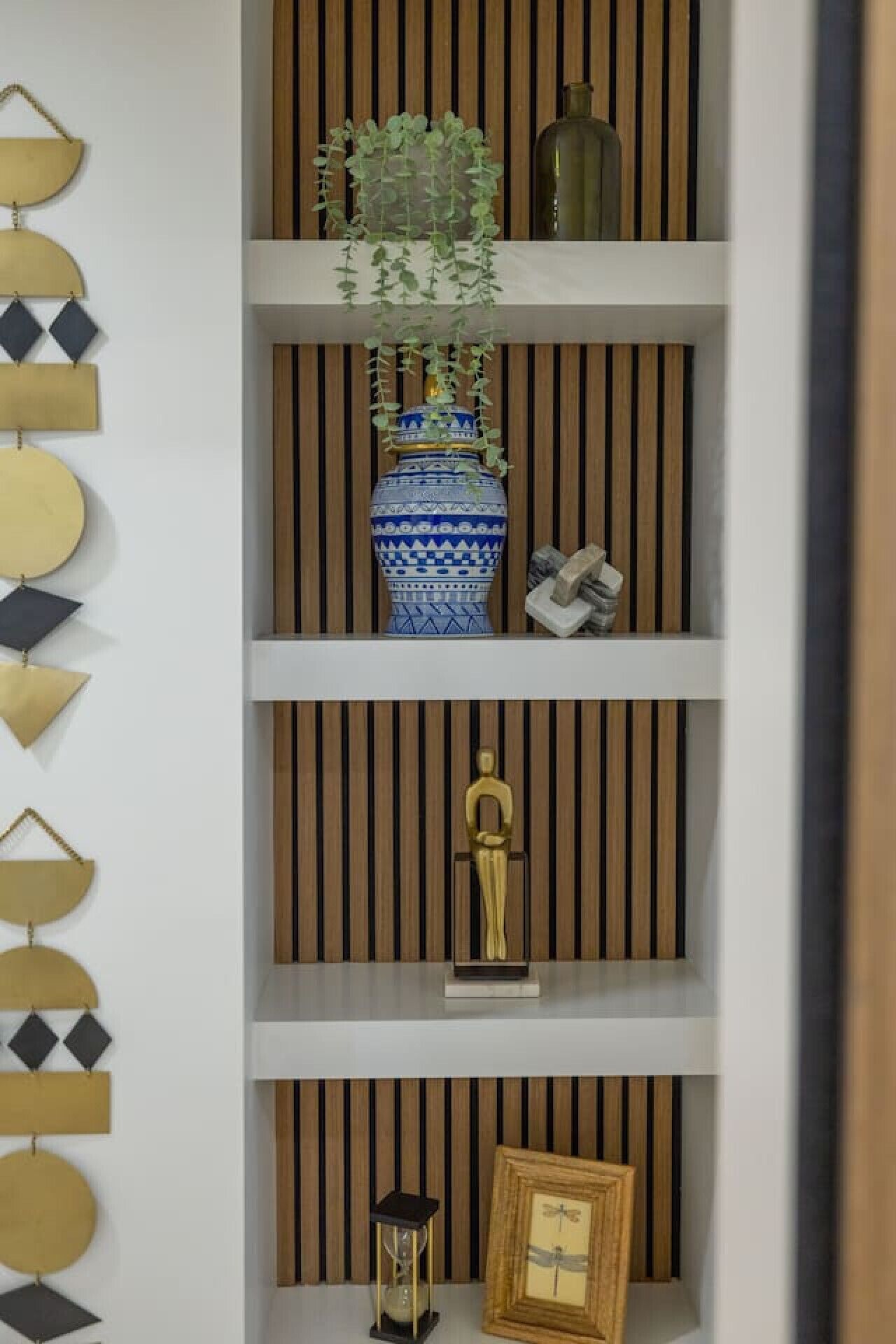A wall with geometric wall art and a wooden slat panel.