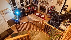 Een woonruimte met meerdere niveaus, een trap, een open haard en een kerstboom.