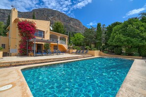 A swimming pool with clear blue water, surrounded by a building with a balcony and lounge chairs. - Classic and cheerful house  with private pool in Javea, Costa Blanca, Spain for 10 persons (Javea)