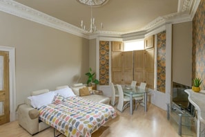 Un dormitorio con cama, una mesa de comedor de vidrio y una televisión.