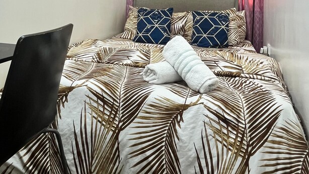A bedroom with a bed, a chair, and a nightstand. - Cozy Central Room, Shared Bath & Kitchen (Abu Dhabi)